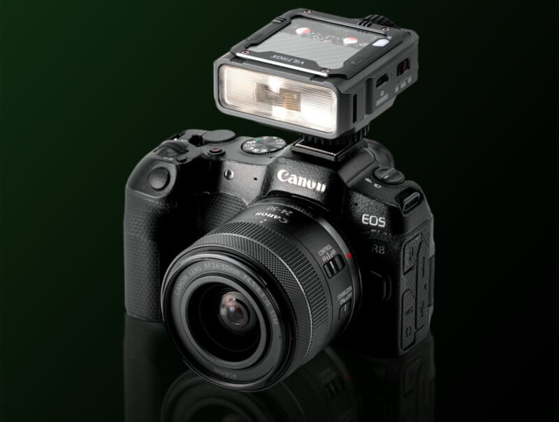 A Canon EOS digital camera with a zoom lens attached and an external flash unit mounted on top, displayed against a dark green background.