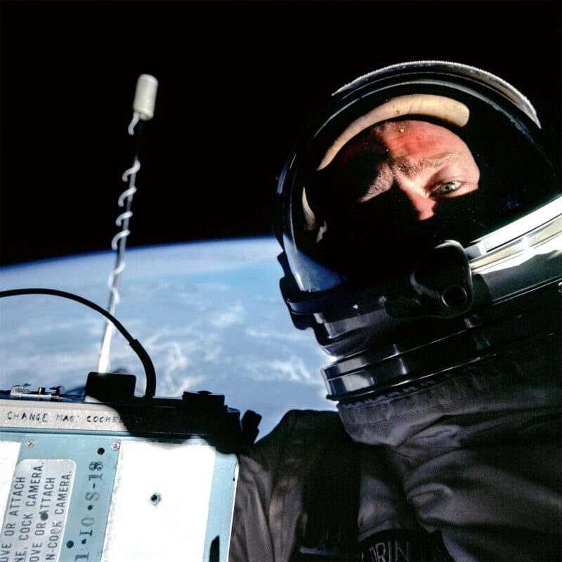 Un astronauta en traje espacial se toma una selfie en el espacio, con partes de la Tierra y la nave espacial visibles al fondo. La luz del sol brillante iluminó la mitad de la cara y el casco del astronauta.