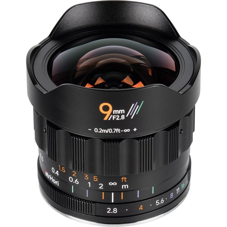 A 9mm f/2.8 camera lens with a wide, curved front element, focus and aperture markings, and a petal-shaped lens hood, photographed against a white background.