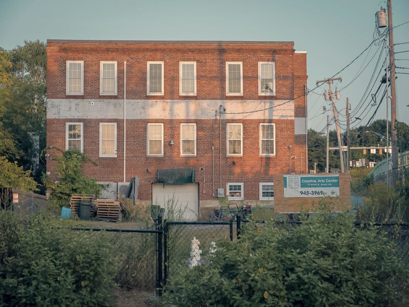 The same brick building photo with an AI preset applied, enhancing oranges and muting other tones.