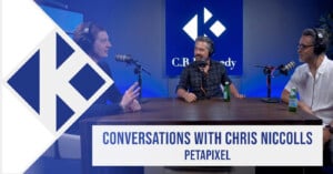 Three men sit at a podcast table with microphones, having a discussion. Behind them is a blue screen with the C.R. Kennedy logo. Text on screen reads “Conversations with Chris Niccolls, PetaPixel.”.