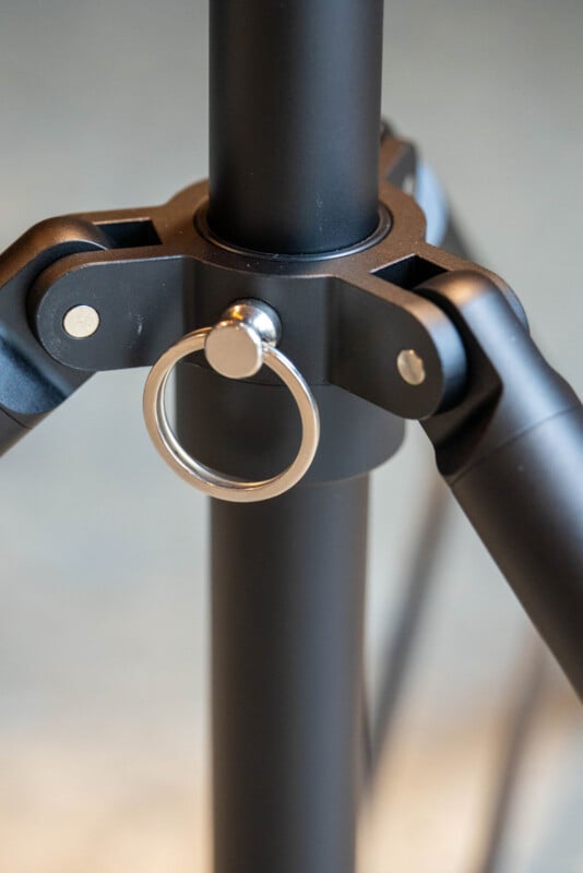 Close-up of a black tripod leg joint with a silver metal ring attached to the center, showing the tripod’s sturdy construction and adjustment mechanism.