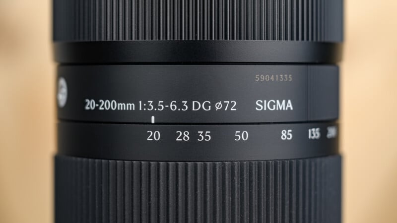 Close-up of a Sigma camera lens showing focal lengths from 20mm to 200mm, aperture range 1:3.5-6.3, and a 72mm filter thread size, with fine textured focus and zoom rings.
