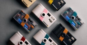 Nine retro-style cameras in various colors and designs are arranged in a grid pattern on a gray surface. Each camera has a unique combination of color accents and the label “Flashback” near the lens.