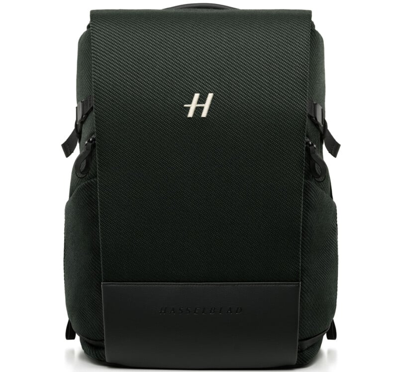A sleek, dark green backpack with a textured surface, featuring a prominent silver "H" logo on the front and "HASSELBLAD" embossed on a black leather section at the bottom.