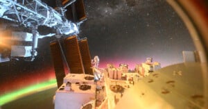 An astronaut performs a spacewalk outside the International Space Station, with solar panels visible and Earth's glowing green and pink auroras, as well as stars, in the background.