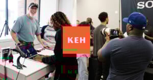 A smiling man speaks with a woman at a counter, while another man photographs a group with a camera. The orange KEH logo is centered between the two scenes.