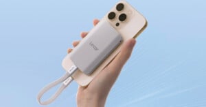 A hand holds a white smartphone with a silver Lexar external solid-state drive (SSD) attached to its back. A white strap labeled Lexar hangs from the SSD, and the background is a gradient light blue.