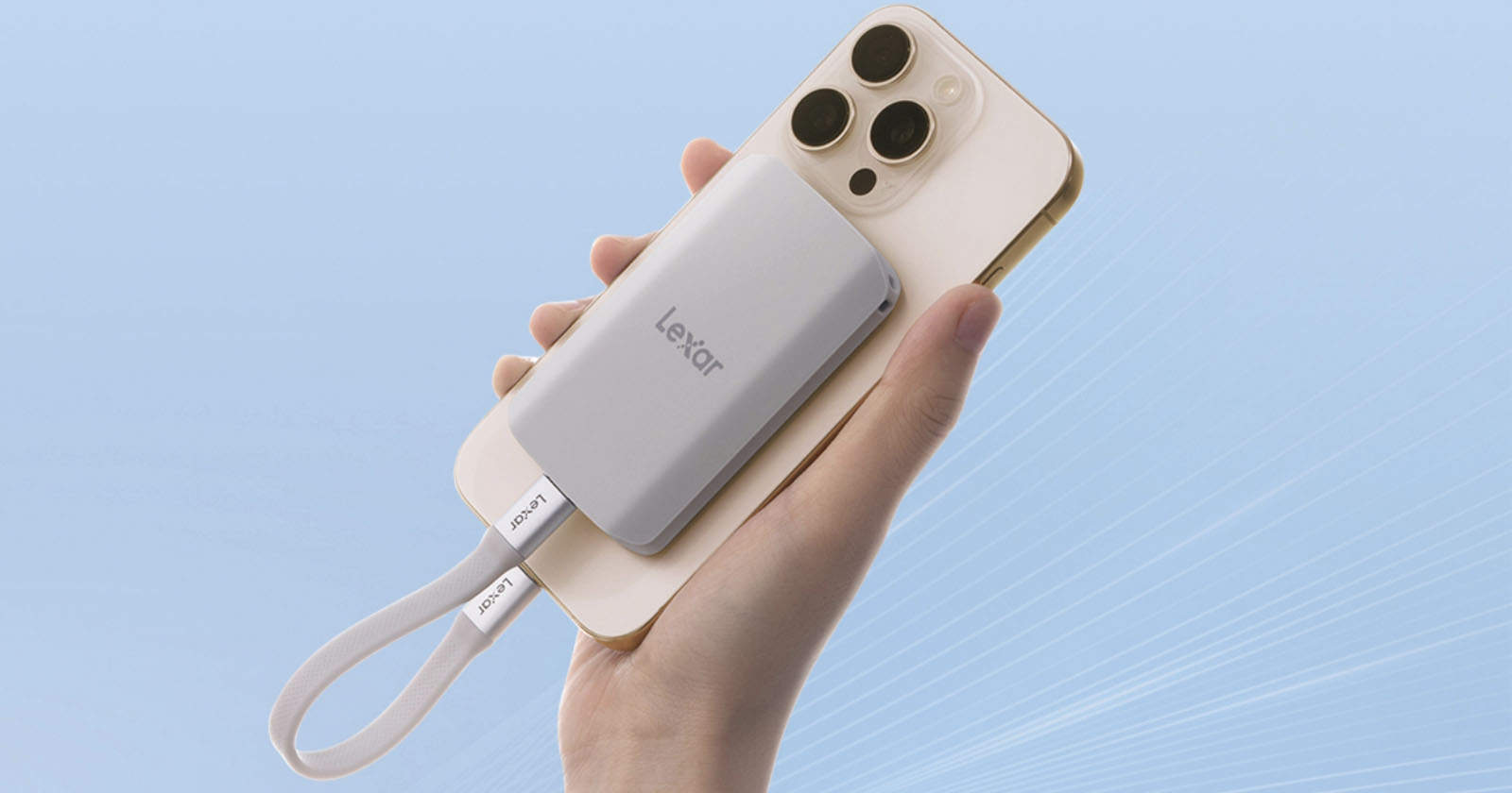 A hand holds a white smartphone with a silver Lexar external solid-state drive (SSD) attached to its back. A white strap labeled Lexar hangs from the SSD, and the background is a gradient light blue.