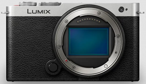 Vista frontal del cuerpo de la cámara digital sin espejo Lumix sin lente, que muestra el sensor, el mango negro texturizado y el borde plateado. La cámara tiene un diseño sencillo y moderno.