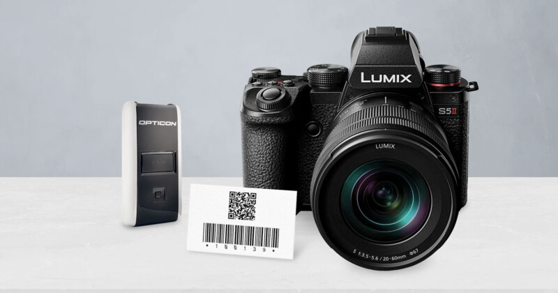 Cámara Lumix S5 II, escáner de código de barras Opticon y tarjeta que muestra un código QR con un código de barras, todo colocado sobre una superficie blanca con un fondo gris claro.