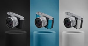 Three identical cameras with different grip colors—black, blue, and white—are each floating above matching cylindrical pedestals against black, blue, and white backgrounds.