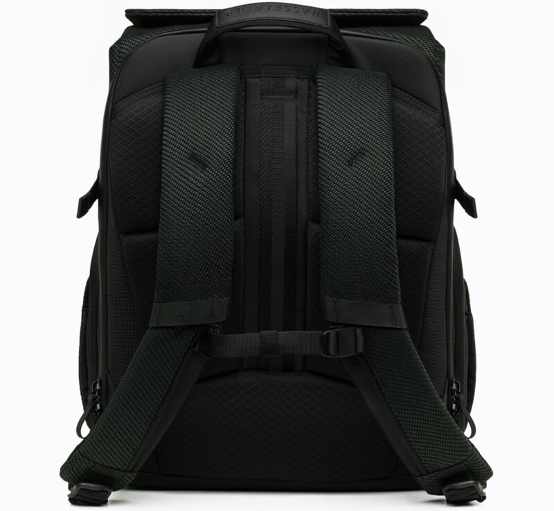 A black backpack shown from the back, featuring padded shoulder straps, a sternum strap, and a textured back panel for comfort and support. The bag has a sleek, modern design with visible zippers on the sides.