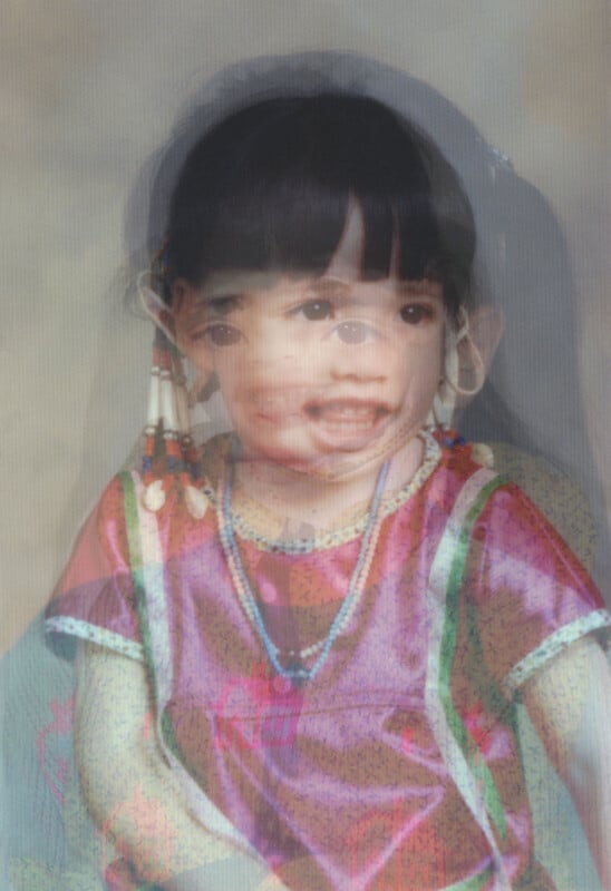 A double-exposed photo of a young child wearing traditional clothing with beaded accessories, resulting in two overlapping faces and layered bodies, creating a surreal and blended portrait effect.