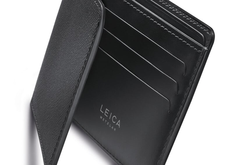 Primer plano de una cartera de cuero negra abierta con múltiples ranuras para tarjetas y "Leica Wetzlar" Impreso en blanco en el interior.