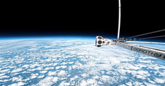 A camera attached to a metallic arm labeled "DOROTHY" captures a view of Earth from high altitude, showing curved horizon, white clouds, and the blackness of space above.