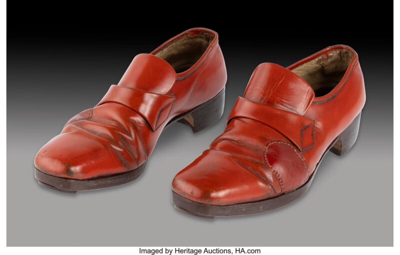 A pair of vintage, red leather heeled shoes with creases and visible wear, set against a gradient background.