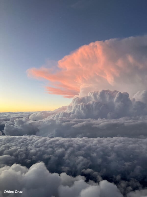 Cloudscape desde arriba, con espesas nubes blancas y grandes nubes cumulonimbus, iluminadas por la suave luz del sol rosa al atardecer o al amanecer. El cielo cambia gradualmente de azul a amarillo. © Álex Cruz.