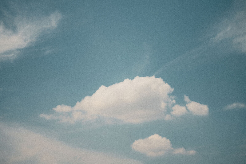 Hay algunas nubes blancas flotando en el cielo azul. Las fotos tienen una textura granulada, lo que les da una apariencia antigua o de película.
