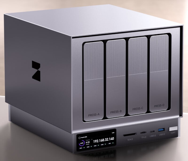 A modern, silver network-attached storage (NAS) device with four labeled drive bays (PRESS-A to PRESS-D), multiple ports, and a small digital display showing network information on the front panel.