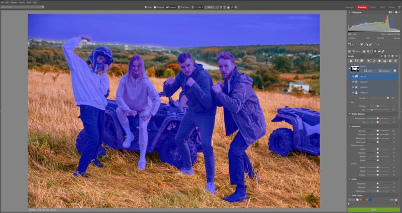 Four people pose in front of two parked ATVs in a grassy field, with hilly landscape in the background. The image editing software interface highlights the people in blue.