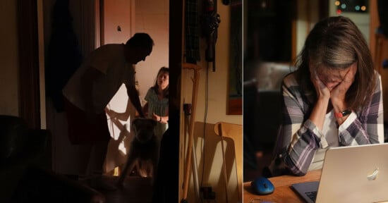 A dimly lit home scene split in two: on the left, a man and a woman greet a dog at the door; on the right, the woman sits at a table, looking down with her head in her hand beside an open laptop.