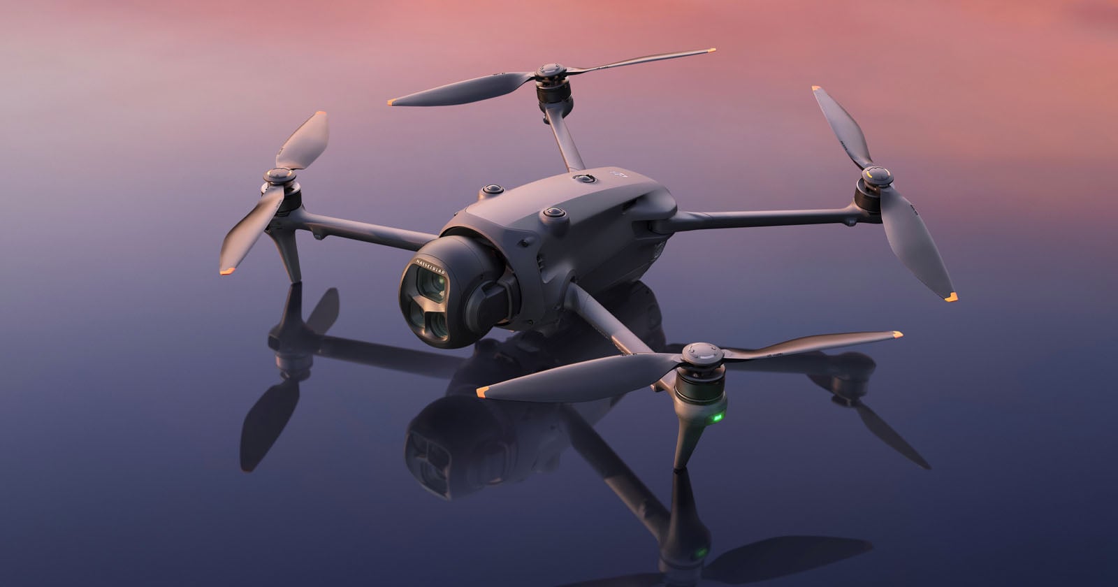 A close-up of a modern quadcopter drone with a camera, resting on a reflective surface under a pink and blue sky at dusk.