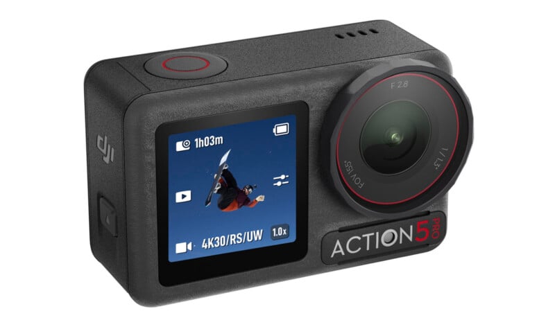 A black DJI Action 5 Pro action camera with a large lens and display screen showing a snowboarder mid-air against a blue sky, with camera settings visible on the screen.