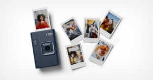 A dark-colored instant camera is surrounded by six printed photos showing people posing, enjoying food, and having fun. The photos are spread out on a white surface.