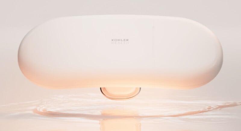 A sleek, oval-shaped white device labeled "Kohler Health" hovers above a smooth surface with a soft orange glow reflecting below it.