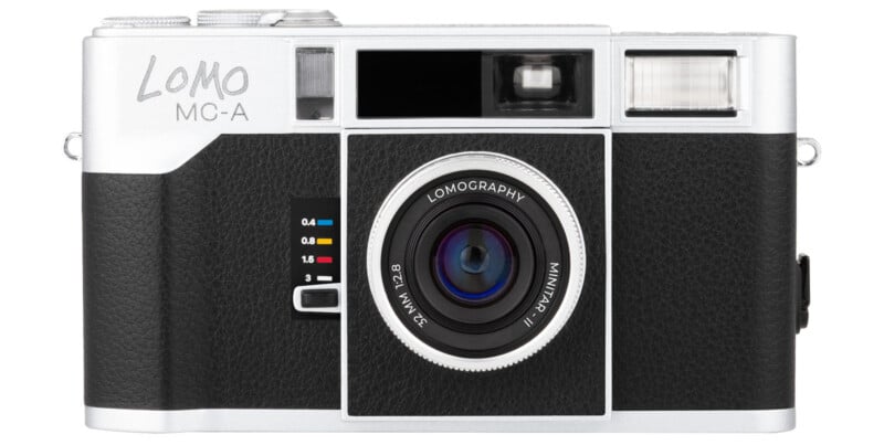 A vintage Lomo camera with a silver top, black textured body, and central lens labeled "Lomography Minitar-1 32mm f/2.8." The camera has a viewfinder and flash on the upper right.