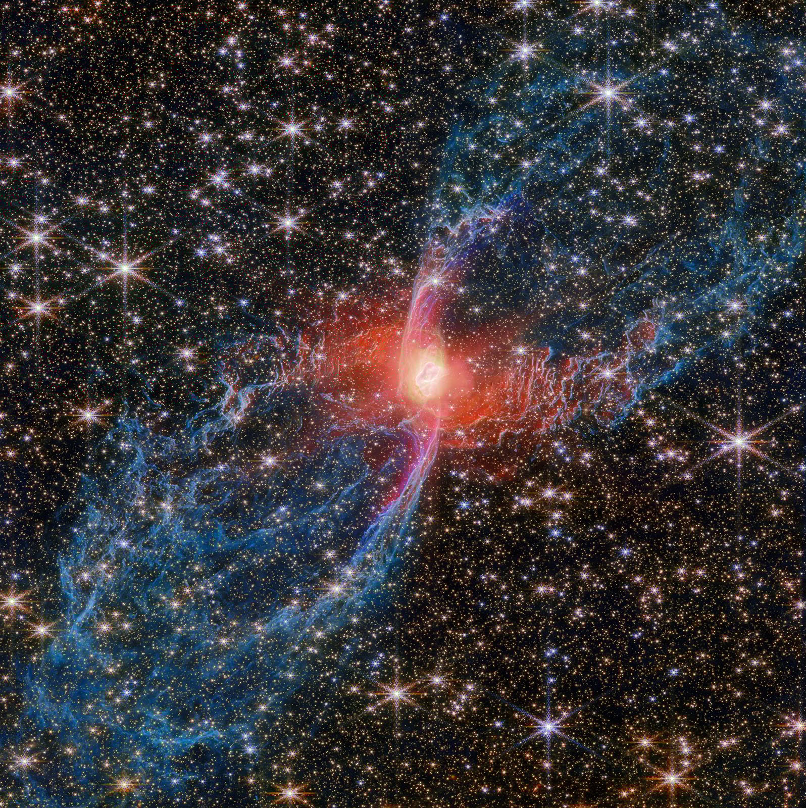 A colorful nebula with bright red, blue, and pink clouds surrounds a glowing central star, set against a dense field of sparkling white stars in deep space.