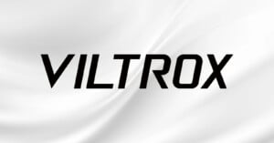 The image features the word "VILTROX" in bold, black, uppercase letters centered on a white background with soft, flowing wave-like patterns.