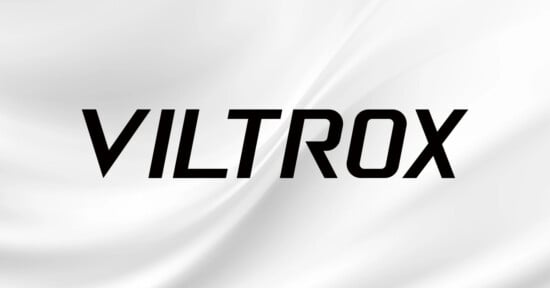 The image features the word "VILTROX" in bold, black, uppercase letters centered on a white background with soft, flowing wave-like patterns.