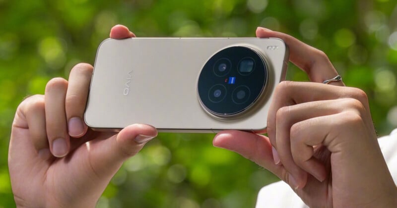 Una persona sostiene un teléfono inteligente Vivo dorado horizontalmente y se enfoca en su gran módulo circular de triple cámara con un fondo borroso de hojas verdes detrás.