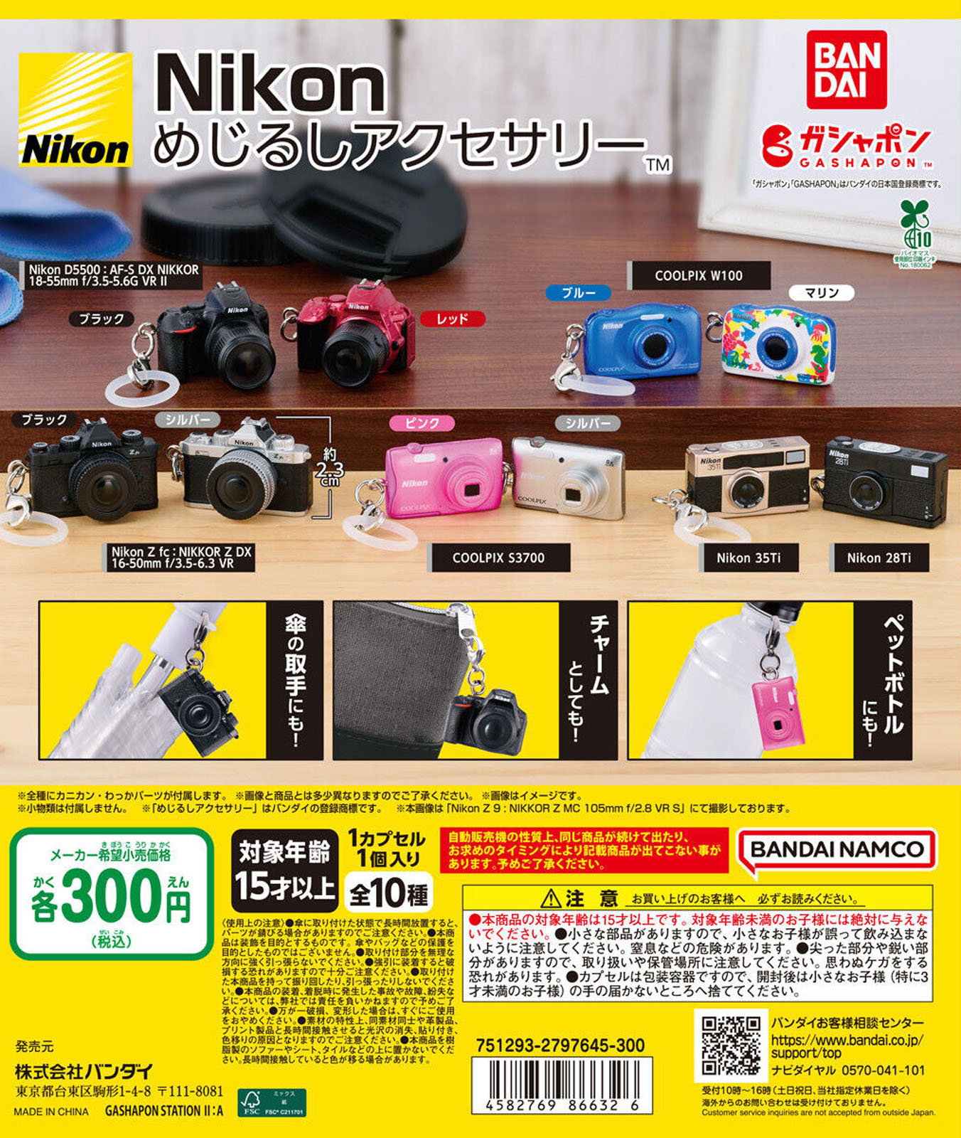 A display of miniature Nikon camera keychains in various colors and models, including DSLR and compact styles, alongside Bandai Namco branding, product details, and pricing information in Japanese.
