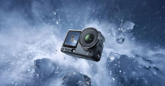 A rugged action camera floats amid splashing water and ice, with its front screen displaying a person snowboarding, highlighting the camera’s durability and suitability for extreme sports.