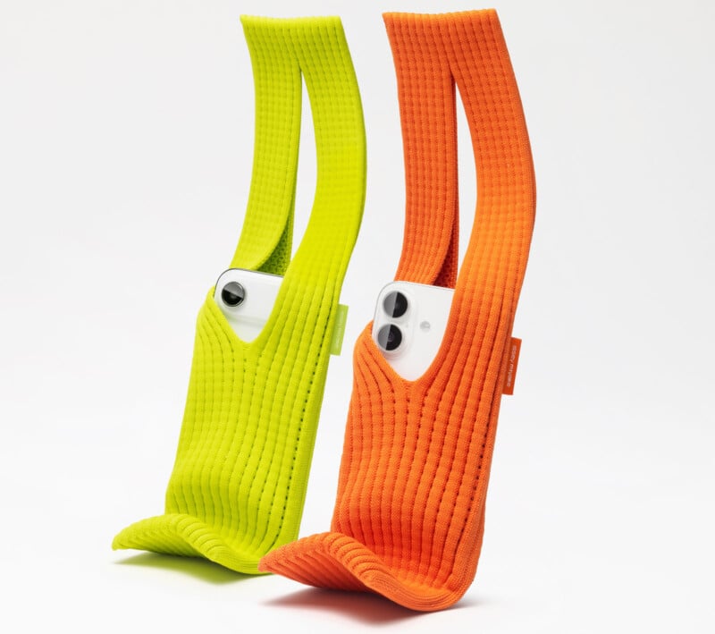 Two smartphones are partially inserted into ribbed, brightly colored knit sleeves—one yellow-green and one orange—standing upright on a white background. The camera lenses of each phone are visible.