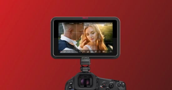 A camera monitor displays a close-up of a man and a woman, with the woman smiling and touching her hair, against a blurred background and a red gradient backdrop.