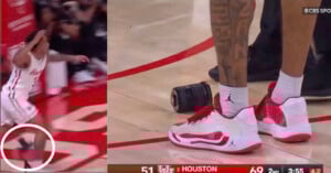 A basketball player steps on a camera near the court boundary; a close-up shows his red and white sneakers next to the camera, with part of his tattooed leg visible. The scoreboard shows Houston leading 69-51.