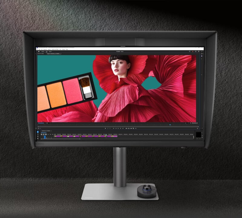 En el monitor de una computadora se muestra un programa de edición de imágenes que muestra a una mujer con un llamativo vestido rojo y una paleta de maquillaje con tres tonos. El monitor se asienta sobre un soporte moderno contra una pared de textura oscura.