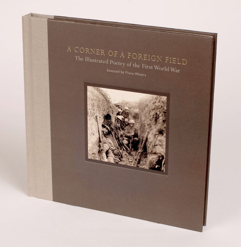 A square, hardcover book titled "A Corner of a Foreign Field: The Illustrated Poetry of the First World War," features a sepia photo of soldiers in a trench on the cover. The book has a beige spine and dark brown cover.
