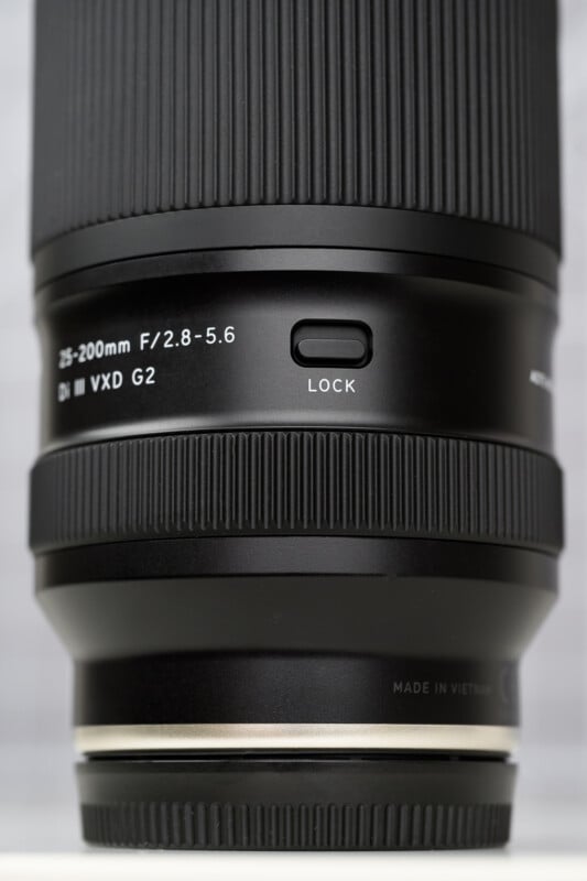 Close-up of a black camera lens showing the 28-200mm F/2.8-5.6 Di III VXD G2 label, a lock switch, and part of the lens barrel with fine ridges and "Made in Vietnam" text at the bottom.