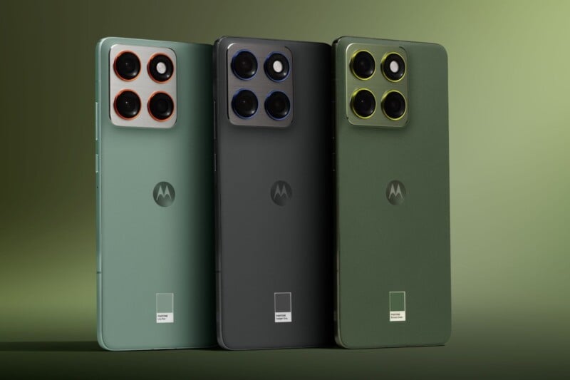 Tres teléfonos inteligentes Motorola se muestran en posición vertical y vienen en verde, negro y verde oscuro, cada uno con un módulo de cámara cuadrado con cuatro lentes y detalles coloridos en la parte posterior. El fondo es verde degradado.