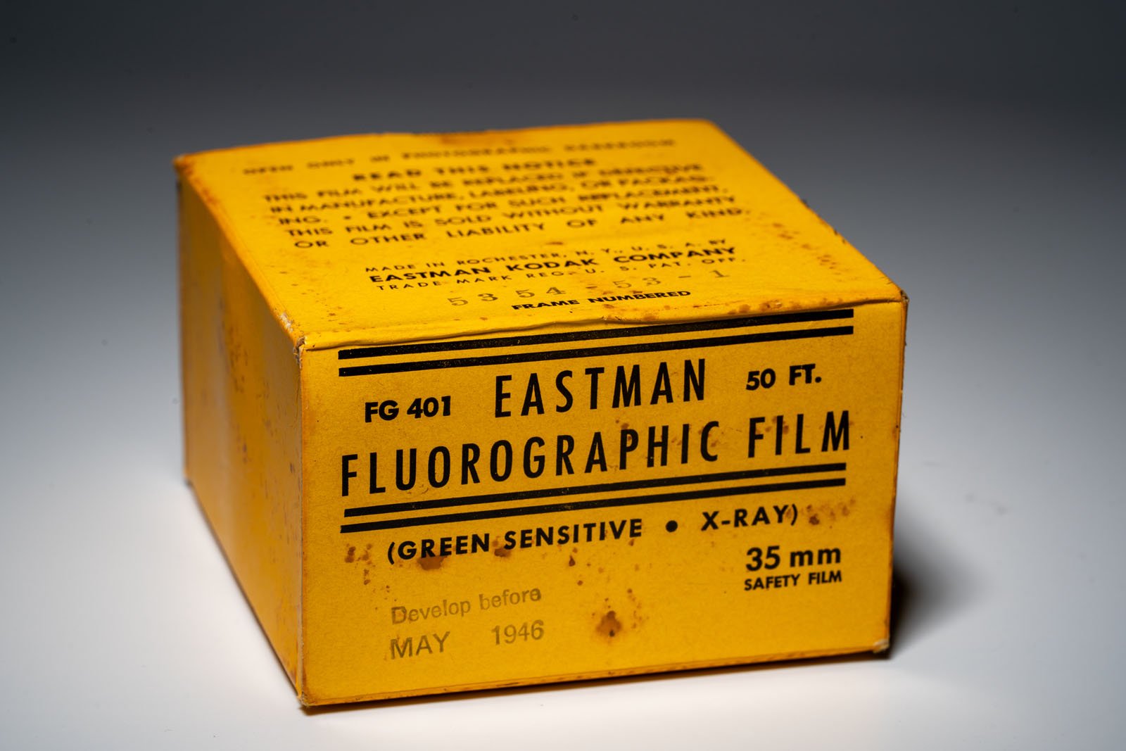 Un cuadro amarillo marcado "Película fluorescente Eastman" Para película de seguridad de 35 mm, 50 pies de largo, sensible al verde, para uso en rayos X, con "Desarrollado antes de mayo de 1946." Esté atento a los signos de edad y óxido.