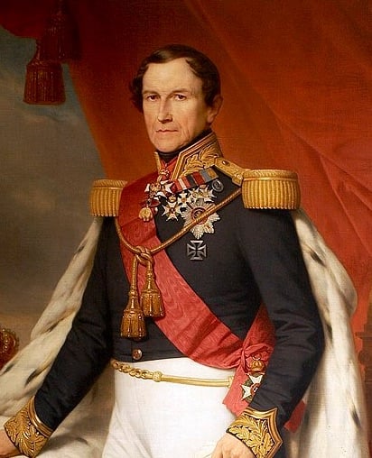 A painted portrait of a man in an ornate military uniform with medals, gold epaulettes, a red sash, and a fur-trimmed cloak, standing against a draped red and gold background.