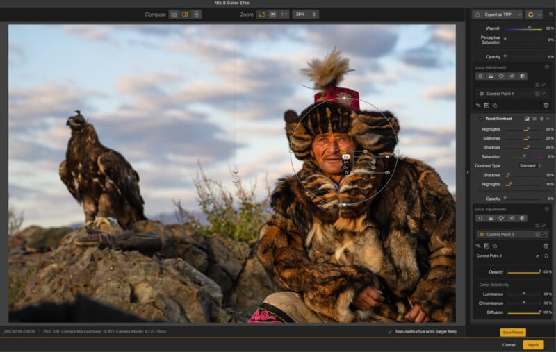 A person wearing fur clothing and a feathered hat sits outdoors on rocks, looking at the camera. A large bird, possibly an eagle, perches on a rock nearby. Photo editing tools are visible on the screen.