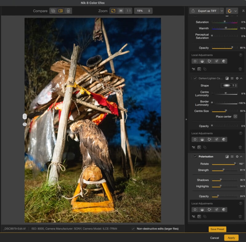 A golden eagle is perched on a yellow stand in front of a rustic wooden shelter at night, with image editing software and adjustment panels visible on the screen.