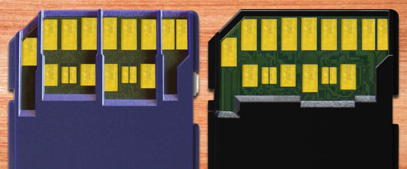 Close-up view of two SD cards with their plastic covers cut away to reveal internal electronic circuits and gold connectors, displayed on a wooden surface.