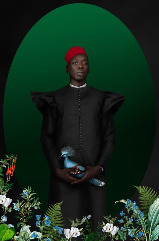 A person in a black outfit with dramatic ruffled sleeves and a red hat stands against a green oval backdrop, holding a blue bird. Colorful flowers and green foliage frame the bottom of the image.